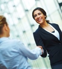 Portrait of successful young business woman shaking hands with a female colleague